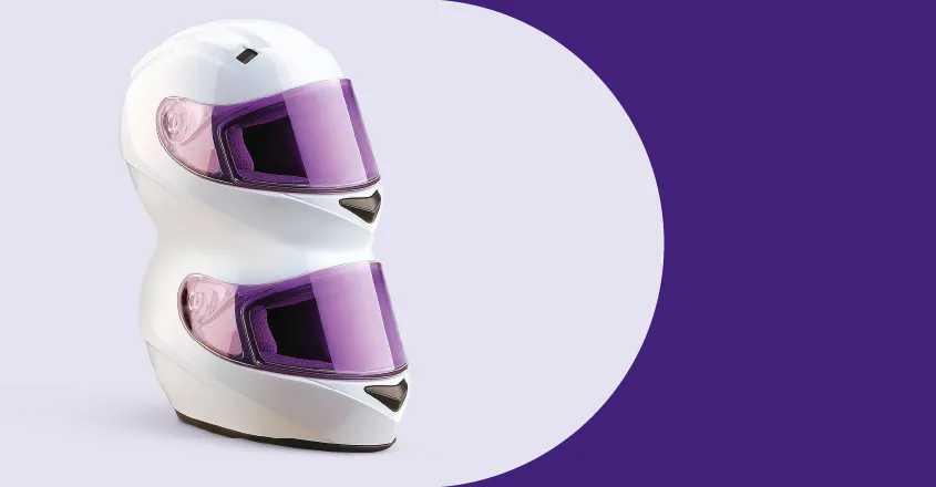 Violetinis fones, jame du motociklo šalmai vienas ant kito.