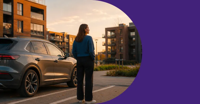 Moteris prie automobilio gyvenamųjų namų kvartale.