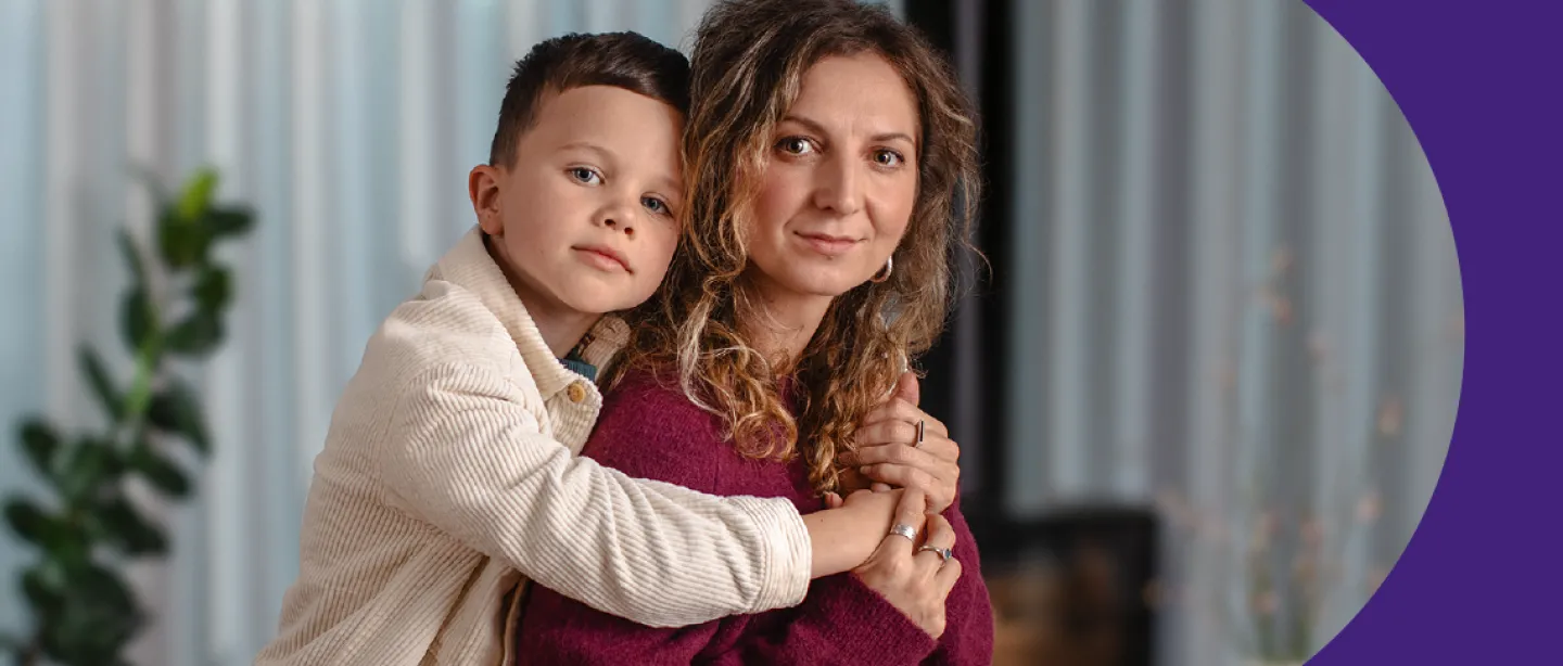 Vaikas stovi apsikabinęs mamą