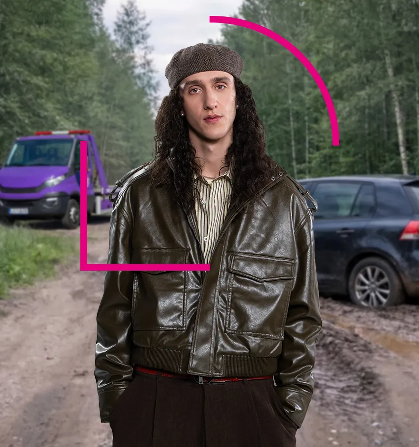 Jaunuolis stovintis prie užklimpusio automobilio, fone taip pat stovi tralas.